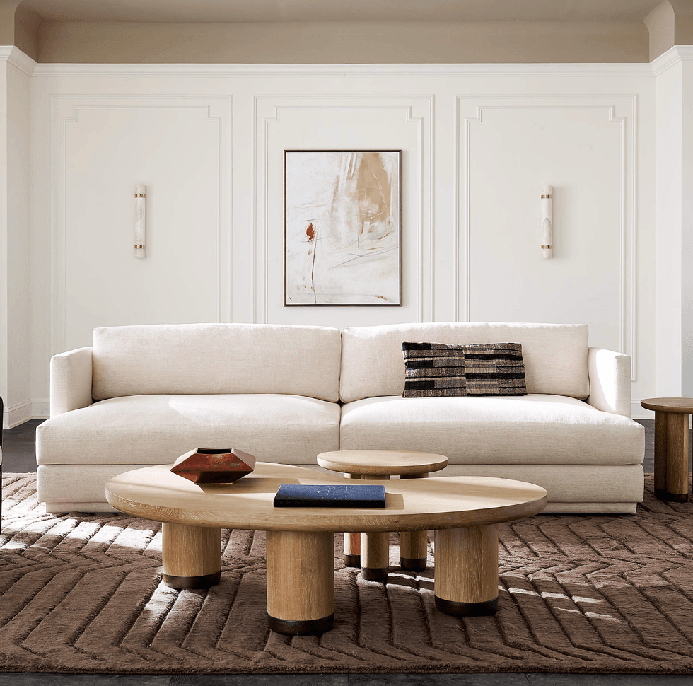 Modern living room with a cream sofa, abstract art, and wooden coffee table.