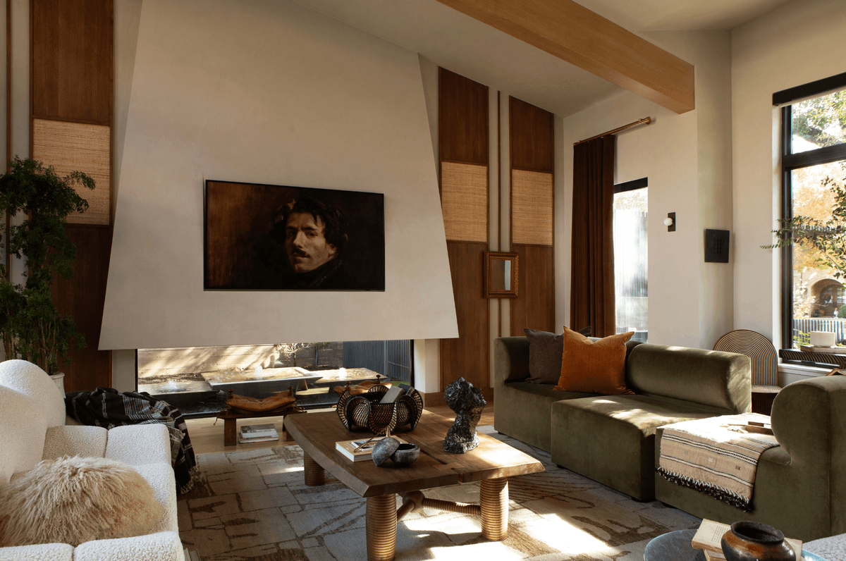 Modern living room with a green sofa, wooden accents, and portrait painting above fireplace.