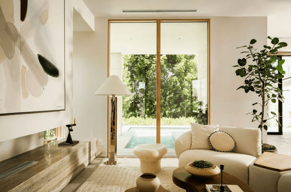 Modern living room with beige decor, large window, pool view, and abstract artwork.