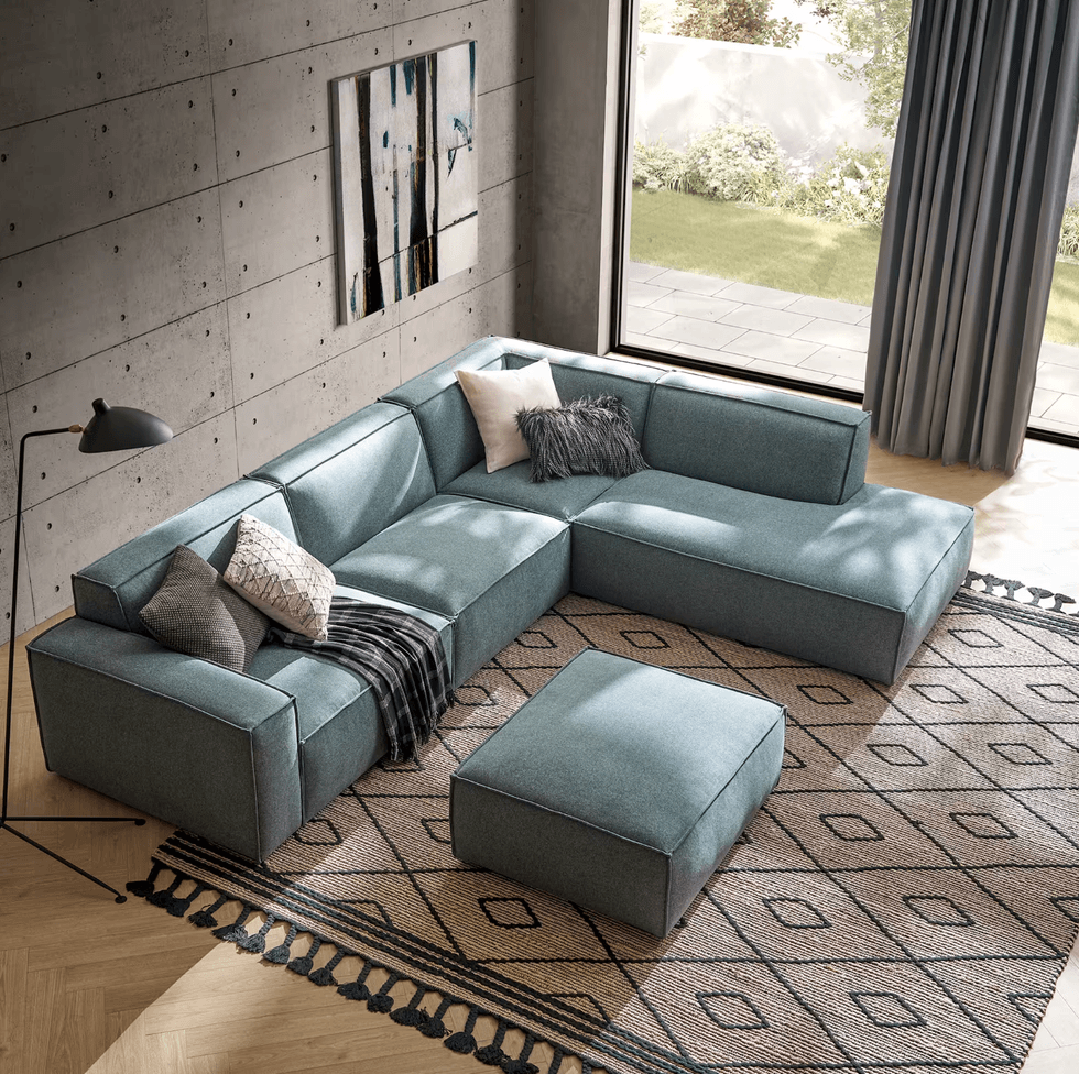Modern living room with blue sectional sofa, patterned rug, and large window.