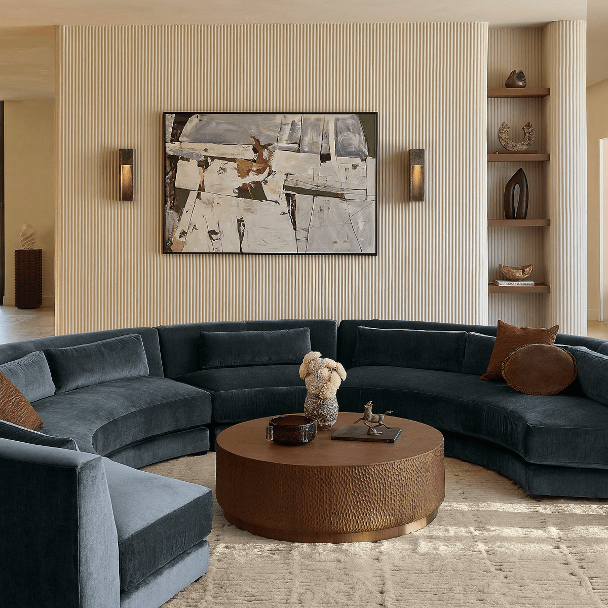 Modern living room with curved sofa, round table, and abstract art.
