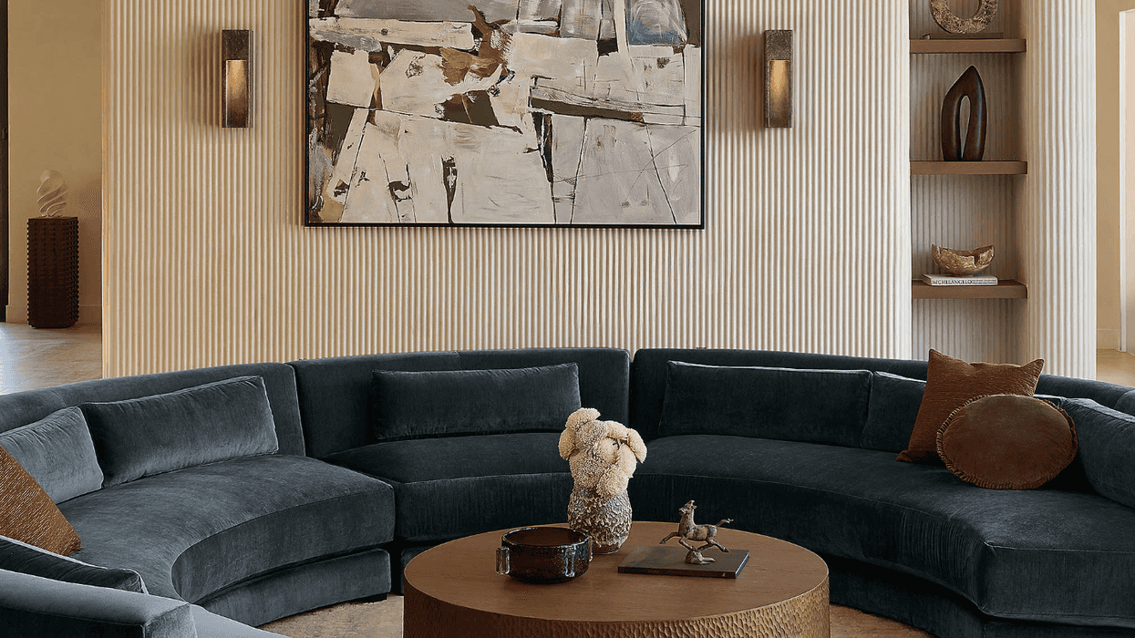 Modern living room with curved sofa, round table, and abstract art.