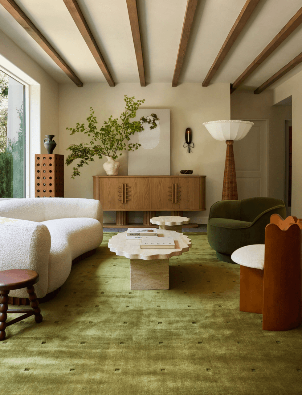 Modern living room with green carpet, cozy couches, and wooden accents.