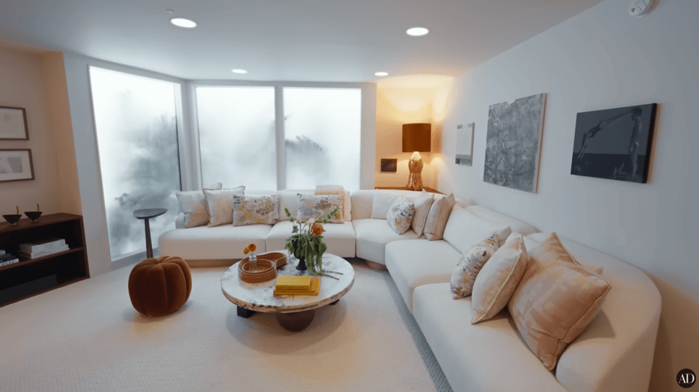 Modern living room with white sectional sofa, round table, and abstract wall art.