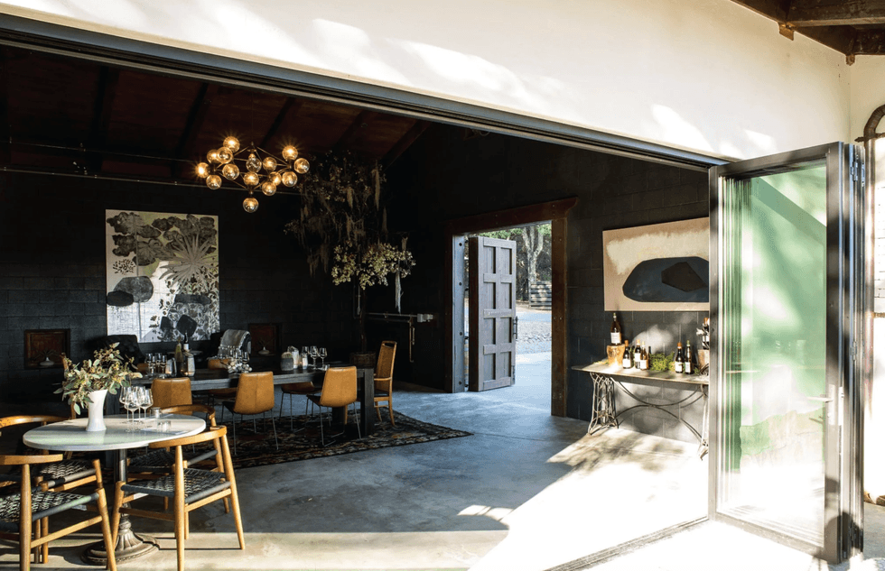 Modern open-air dining room with elegant decor and large open doors.