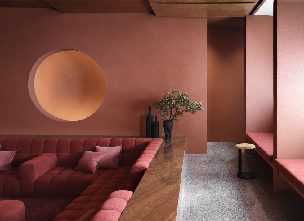 Modern room with red sofas, circular wall feature, and decorative plants.