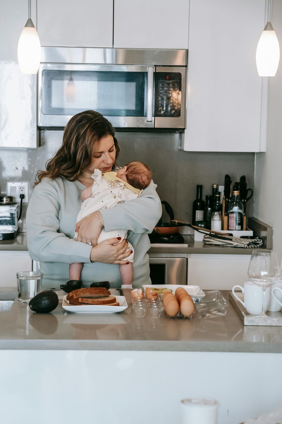 mom holding baby and eating breakfast in kitchen