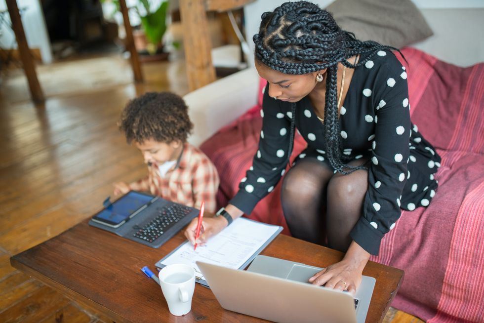 mom working on laptop while son watches cartoons on tablet
