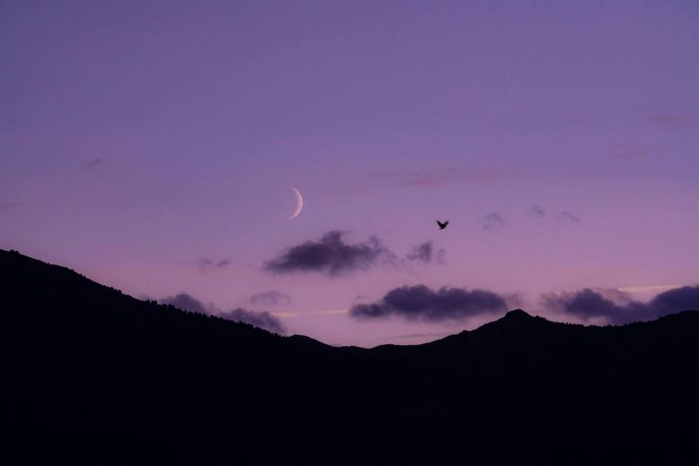 moon in a purple sky over the mountains
