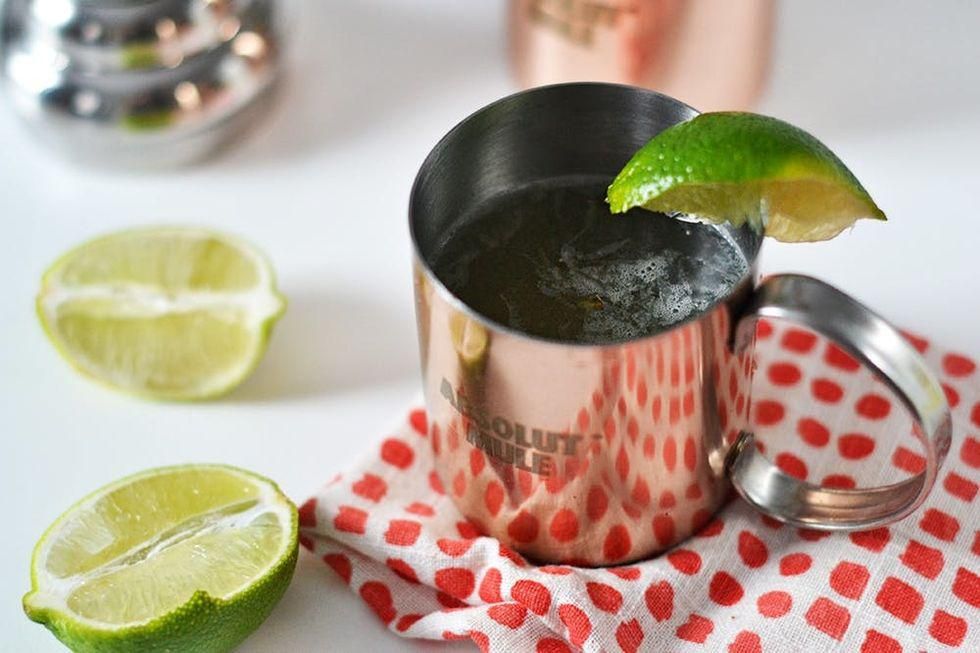 Moscow mule cocktail in a metal container on a red dot towel with limes
