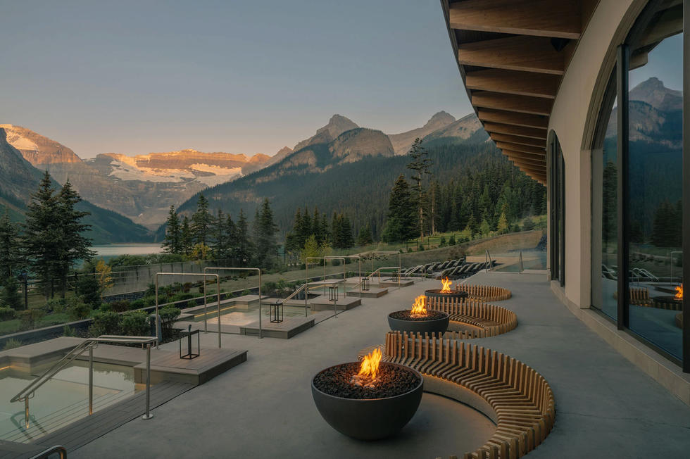 Mountain resort patio with fire pits, seating, and a scenic view of mountains at sunset.