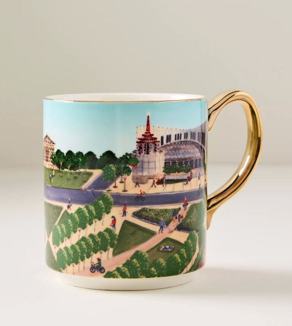 Mug with a colorful cityscape illustration and a gold handle.