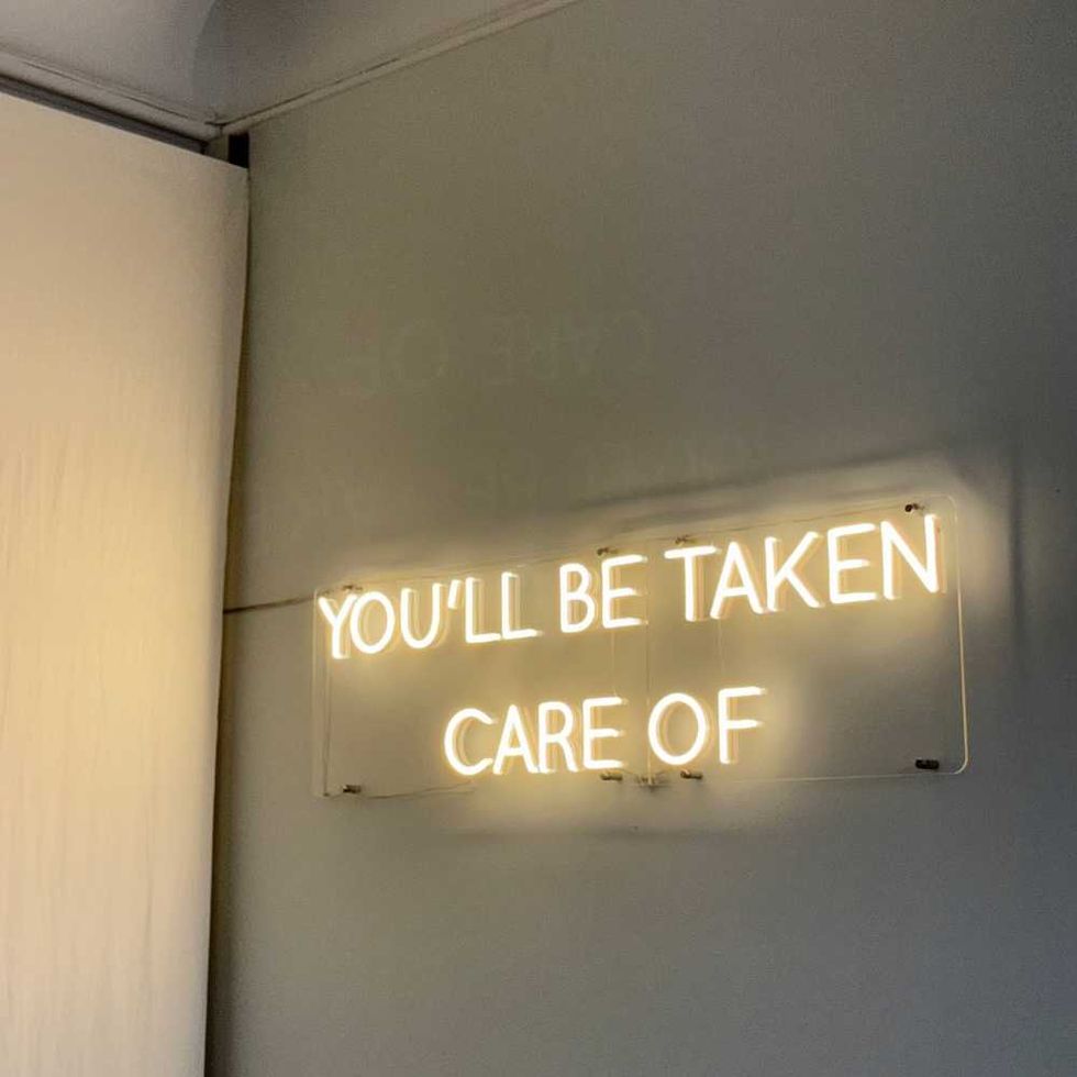 Neon sign on wall reads "YOU'LL BE TAKEN CARE OF."