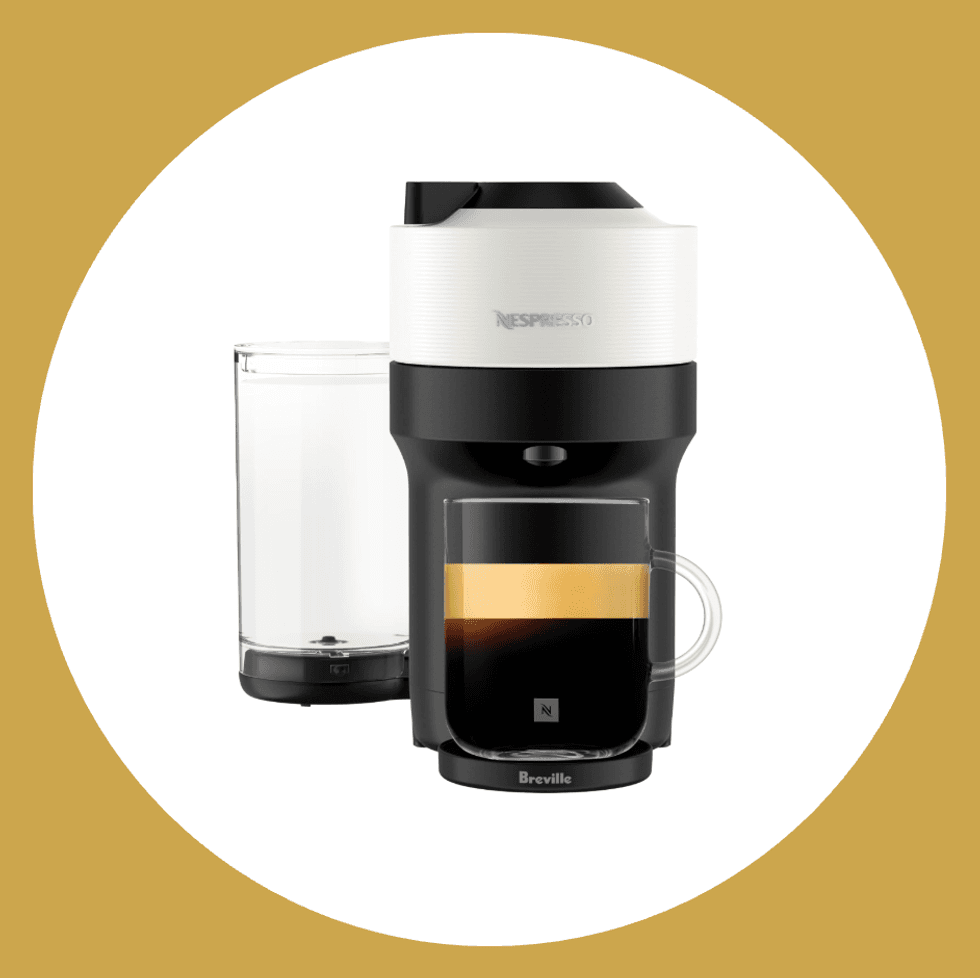 Nespresso coffee machine with clear water tank and brewed coffee in front.