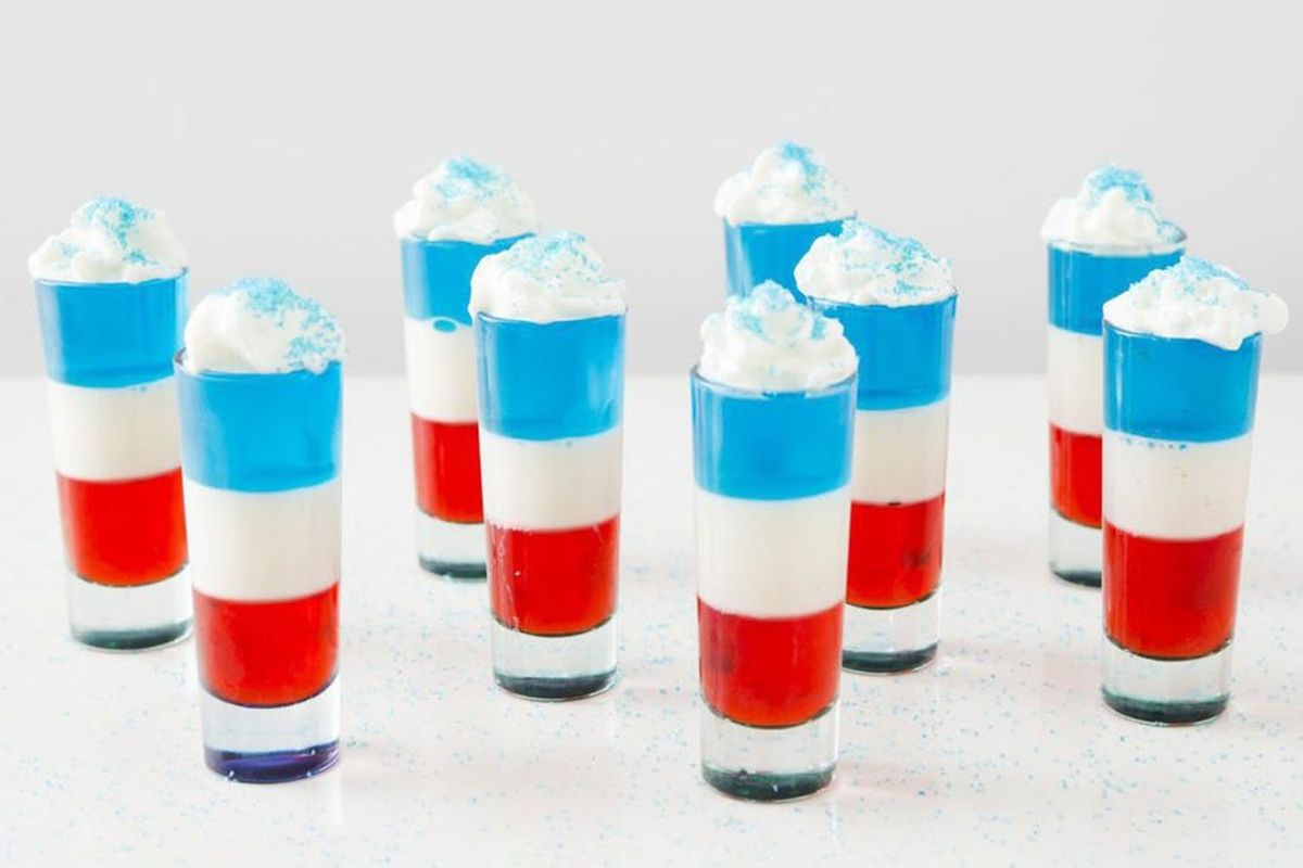 Nine red, white and blue 4th of July Jello shots topped with whipped cream and blue sprinkles