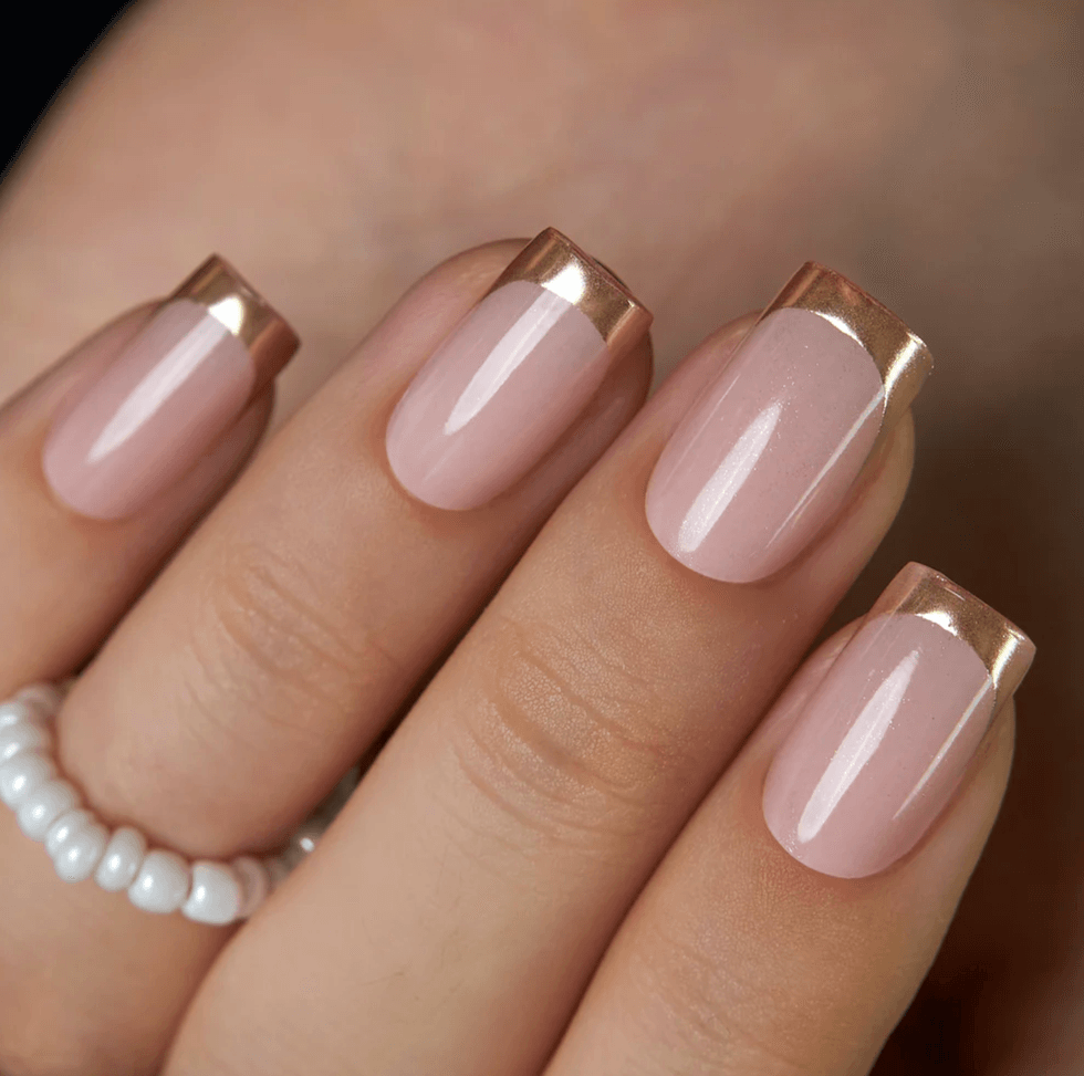 Nude nails with metallic tips and a beaded white ring on the finger.