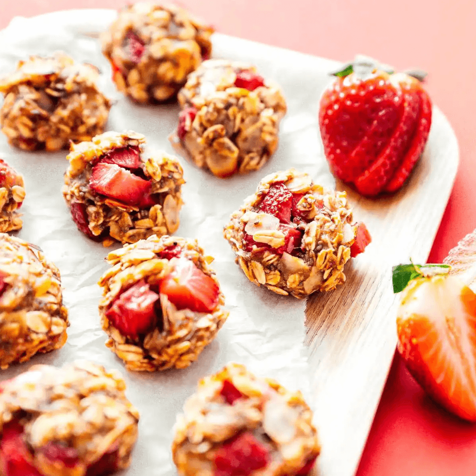 Oat and strawberry clusters on a white tray with fresh strawberries on the side.