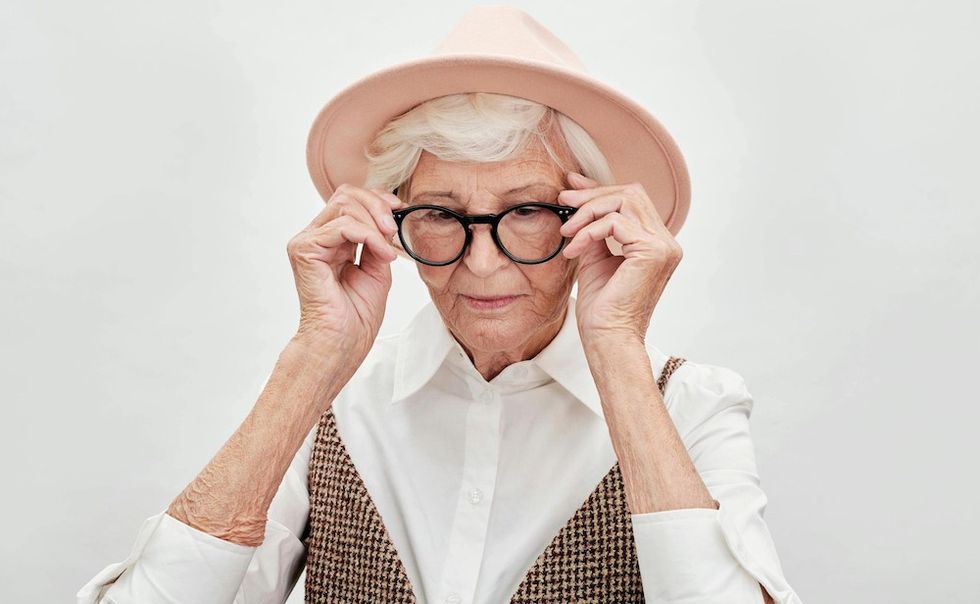 older woman putting on her glasses