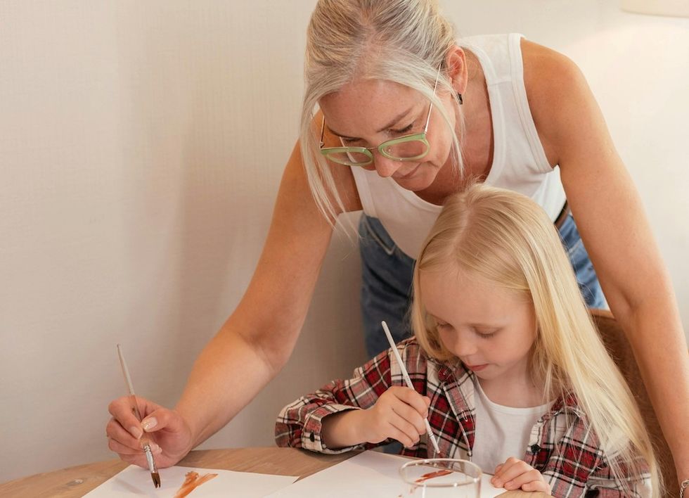 older woman teaching a child how to paint