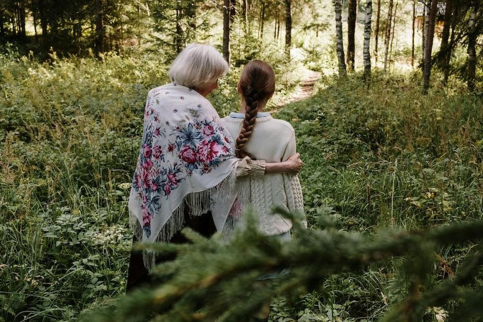 older woman walking through the woods with another woman