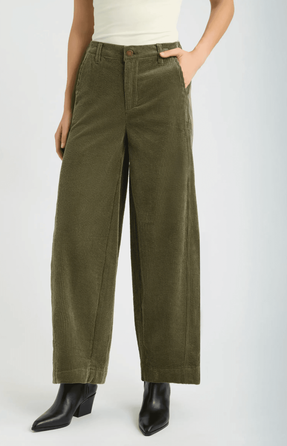 Olive green corduroy pants, hands in pockets, black heeled boots.