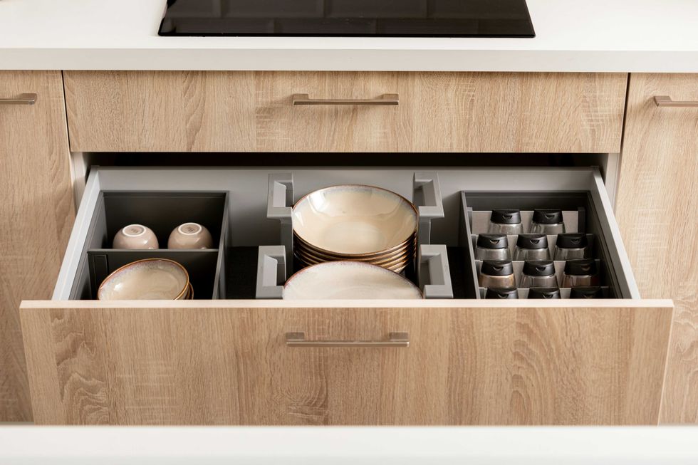 Open kitchen drawer with organized dishes and cups.