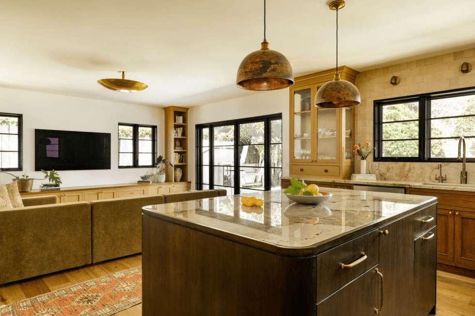 Open kitchen-living area with marble island, rustic lights, and sliding doors.
