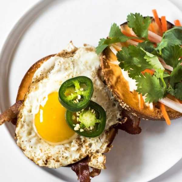 Open sandwich with fried egg, jalape\u00f1os, cilantro, pickled veggies on a bun.