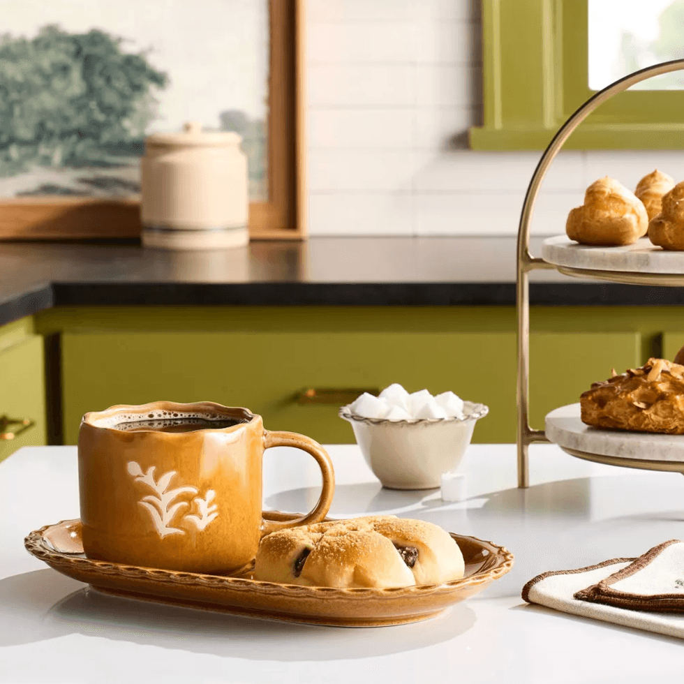 Orange cup with coffee and pastries in a cozy kitchen setting.