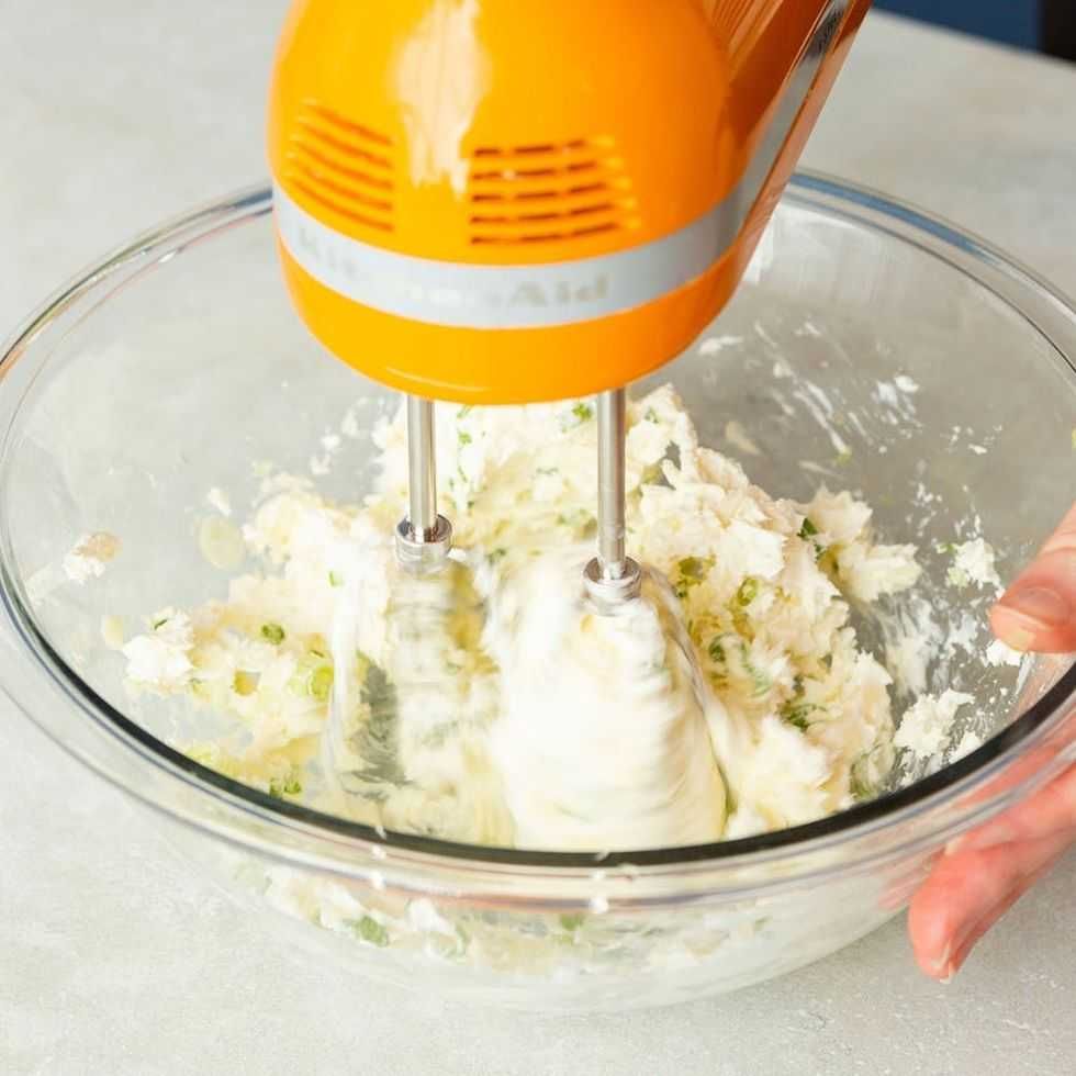 Orange mixer blending ingredients in a glass bowl.