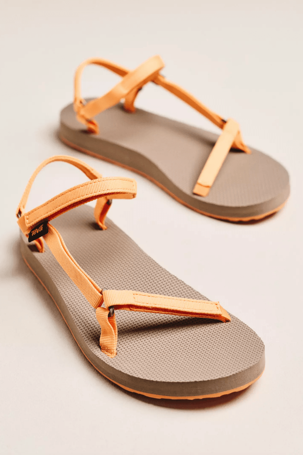 Orange-strap sandals with gray soles on a light background.