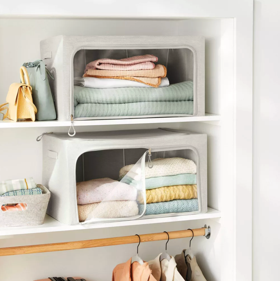 Organized closet with fabric storage bins, folded blankets, and hanging clothes.