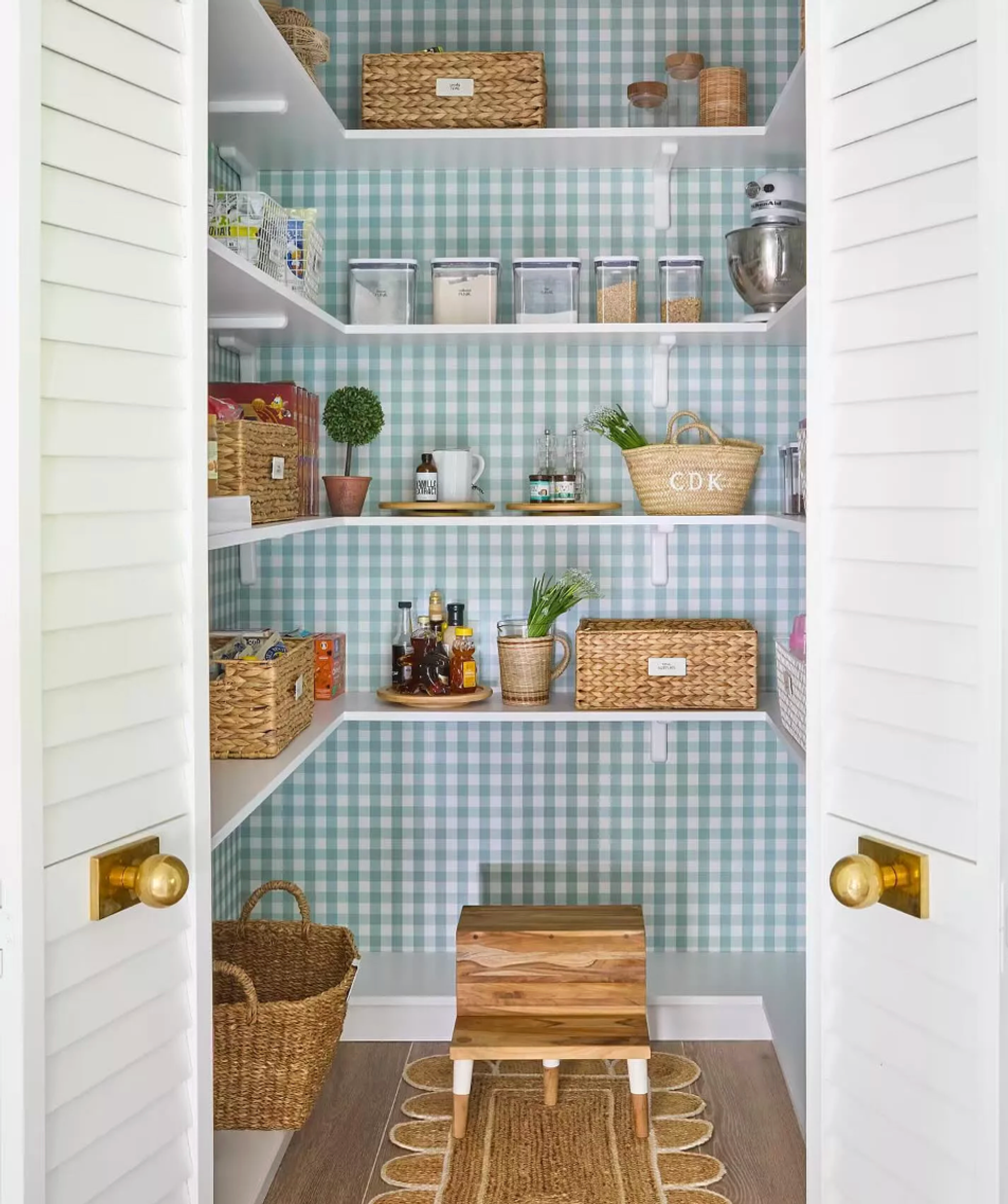 Organized pantry with basket storage and green plaid wallpaper.