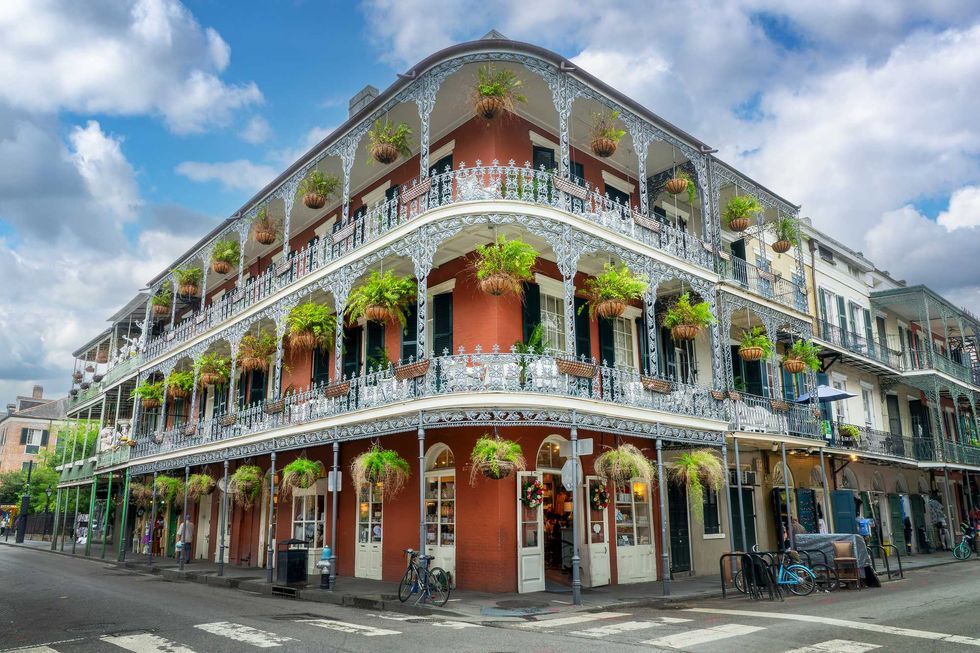 Ornate, iron-laced balconies with hanging plants on a historic brick building.