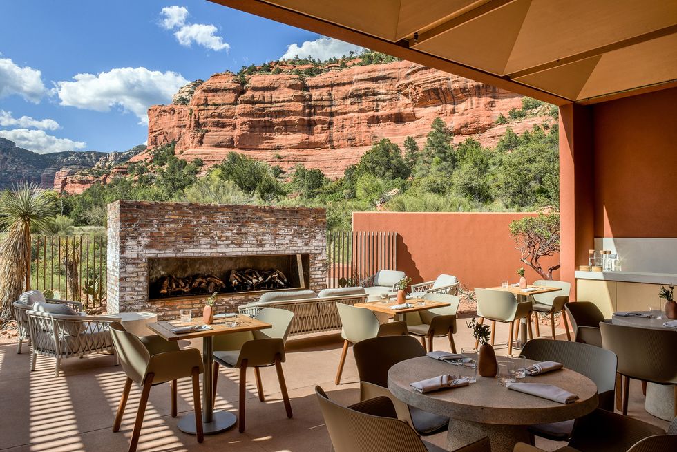 Outdoor patio dining with a view of red rock cliffs and lush greenery.