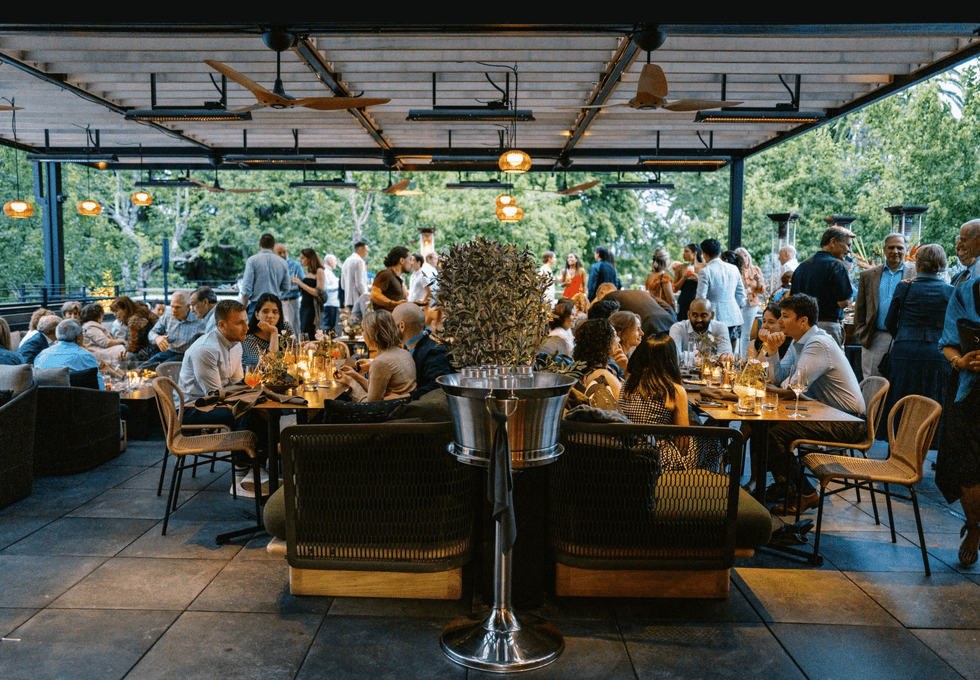 Outdoor restaurant with people dining and socializing under a covered patio.
