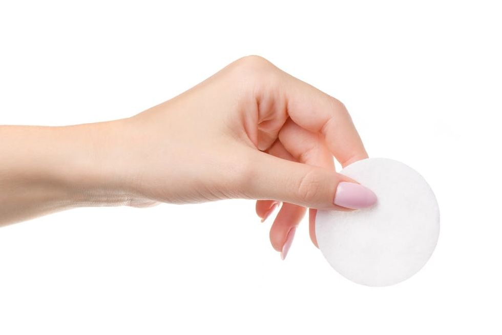 Outstretched hand holding a white cotton round.