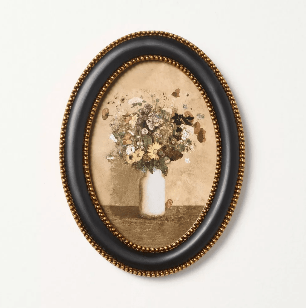 Oval frame with vintage floral painting, gold beaded border, white background.