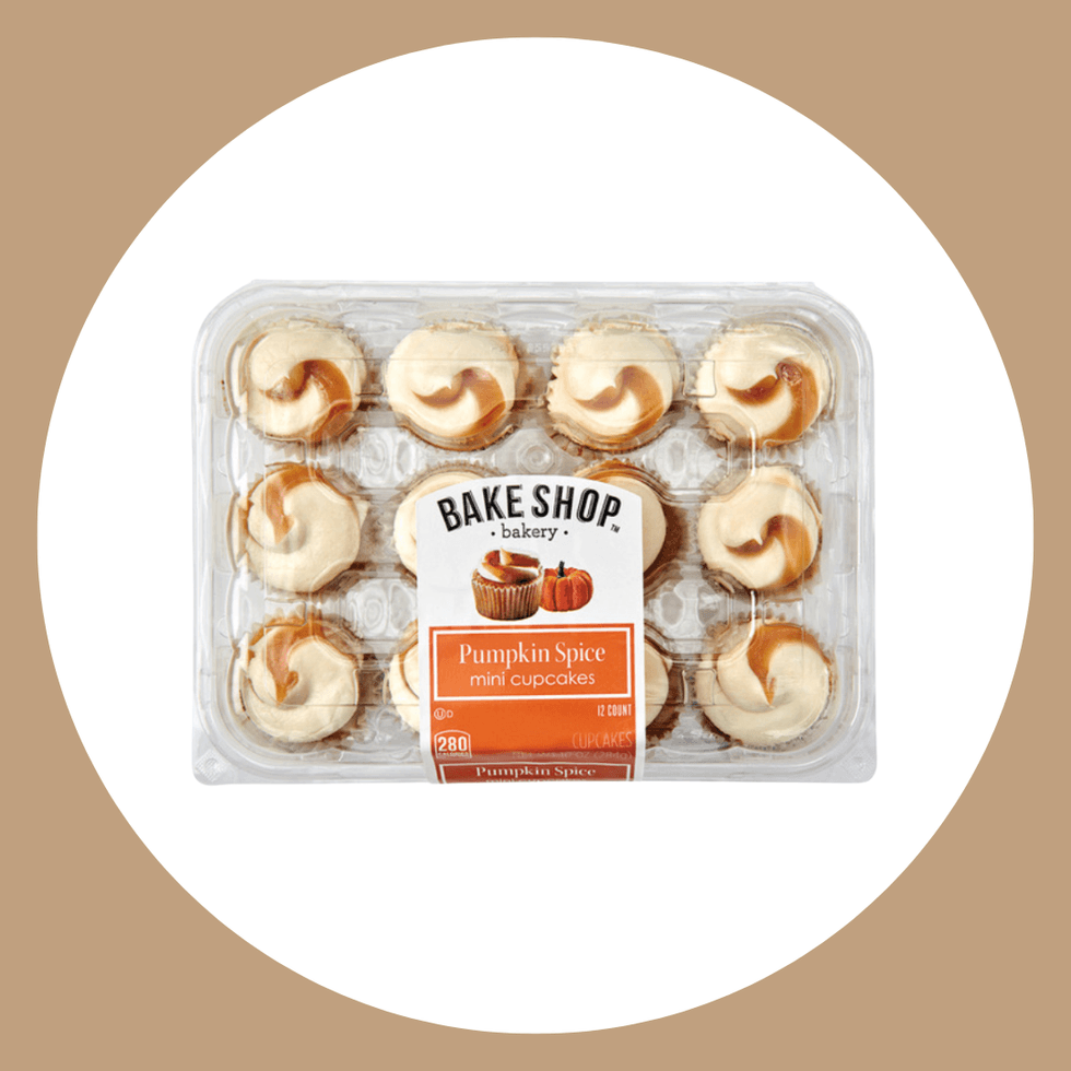 Pack of 12 pumpkin spice mini cupcakes in clear packaging on a tan background.