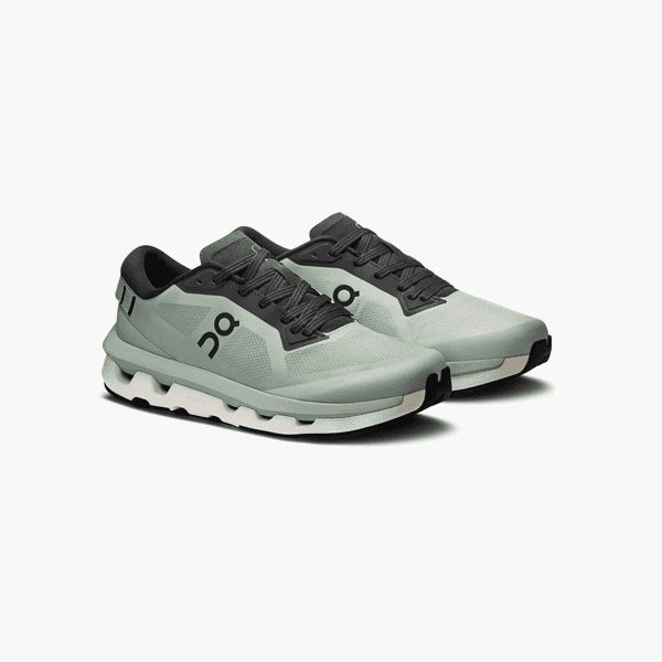 Pair of pale green running shoes with black laces and chunky white soles on a white background.