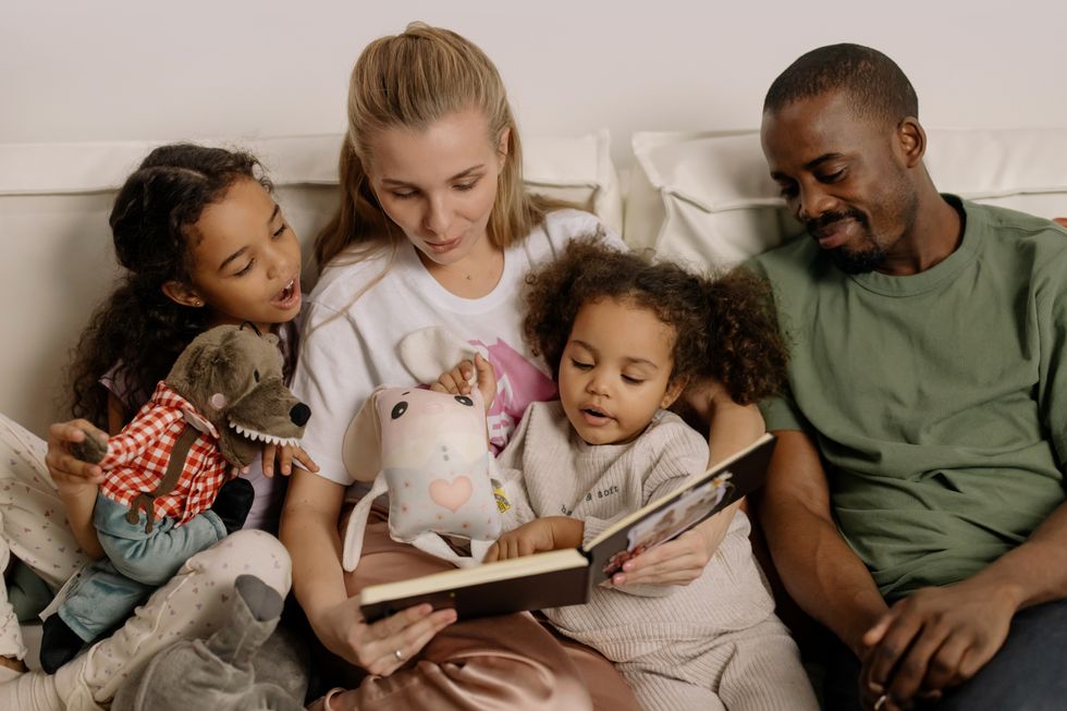Parents reading to their young daughters