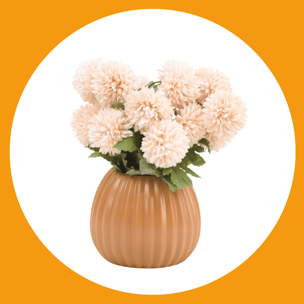 Peach pom-pom flowers in a ribbed brown vase on a white and orange background.
