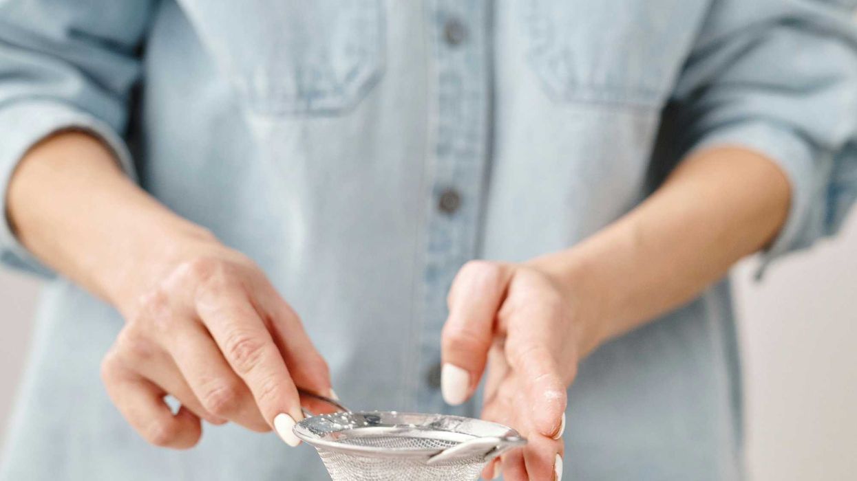 Person dusting powdered sugar on star-shaped cookies.