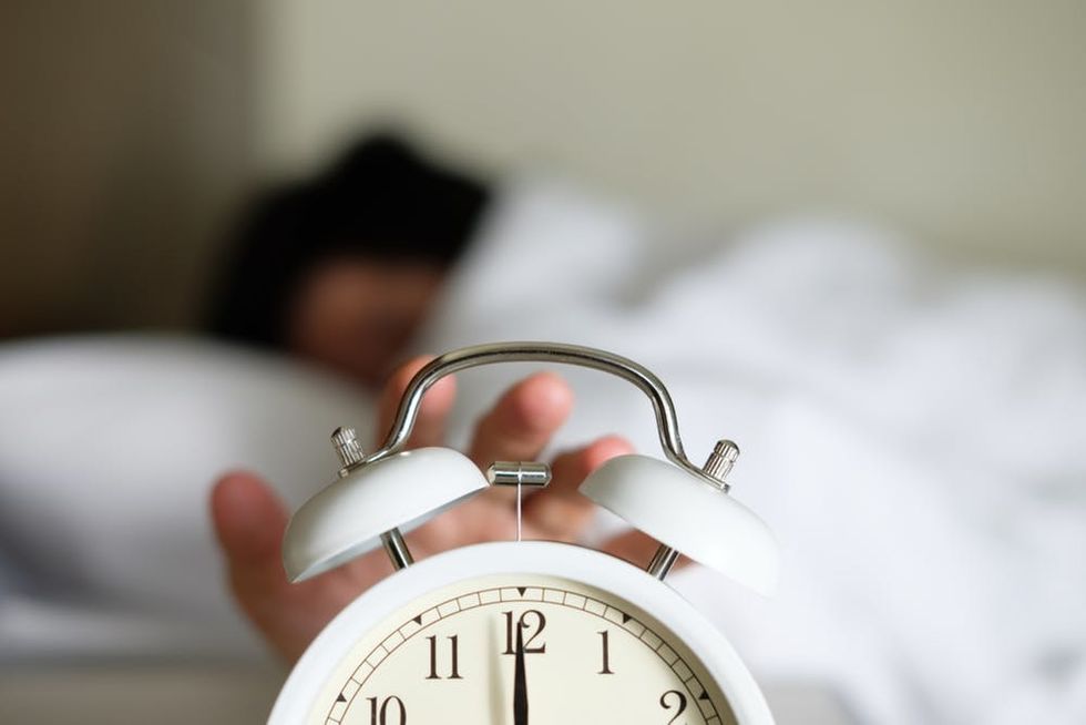 Person hitting snooze button on alarm