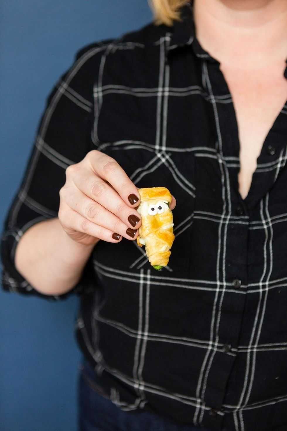 Person holding a croissant-shape snack with googly eyes.