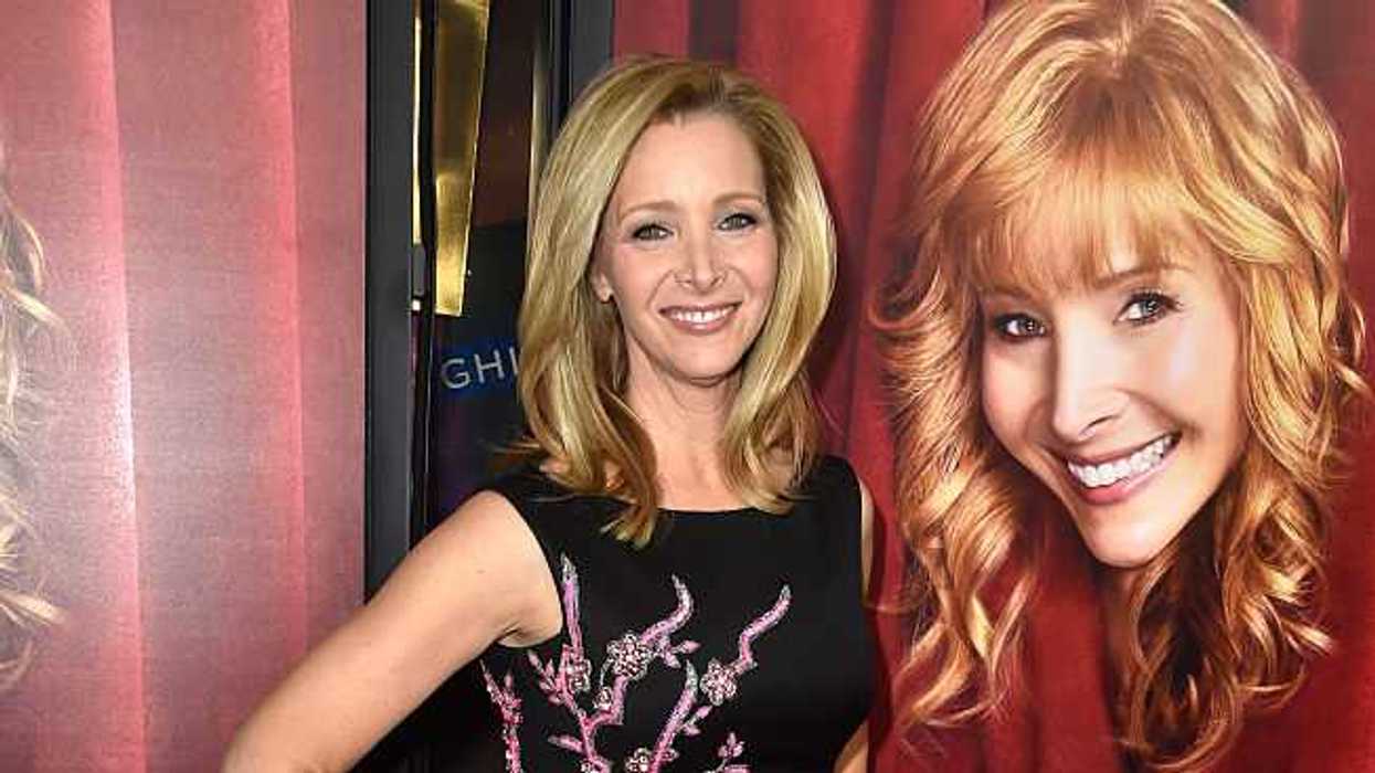 Person in a black dress poses next to "The Comeback" HBO poster.