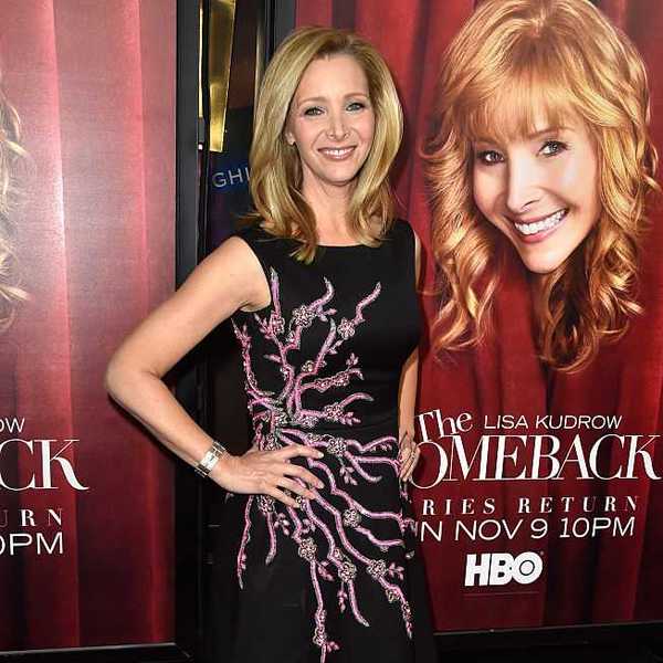 Person in a black dress poses next to "The Comeback" HBO poster.