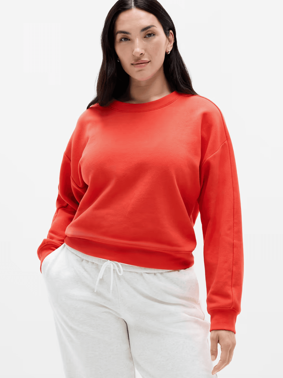 Person in a red sweatshirt and white sweatpants against a white background.