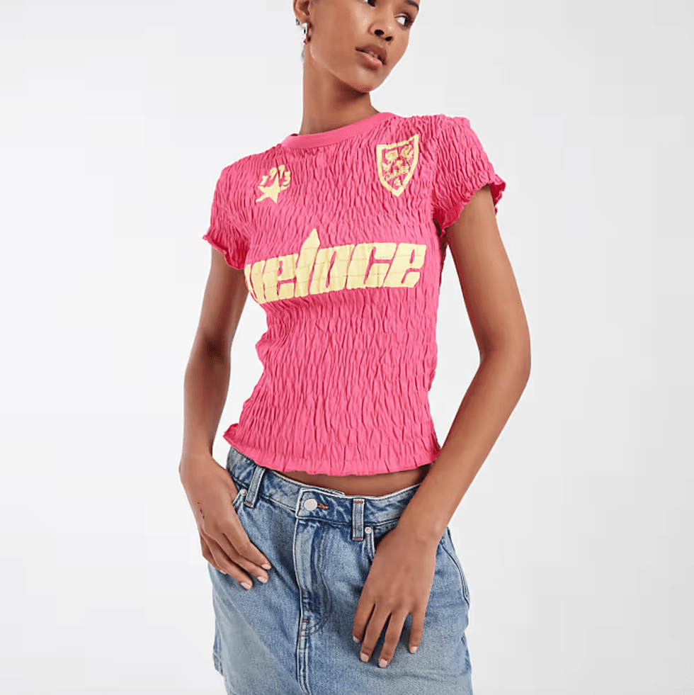 Person in a ruched pink top and denim skirt, against a white background.