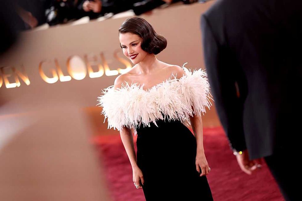 Person in an elegant black dress with a white feathered top at a formal event.